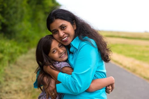 Mother hugs her daughter in summer