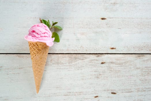 Top view strawberry ice cream waffle cone on wooden background, copy space on side.
