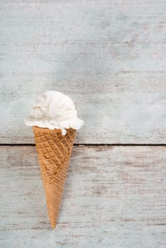 Top view white ice cream wafer cone on bright rustic wooden background. With copy space.