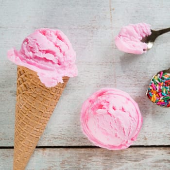 Top view strawberry ice cream waffle cone on wooden background close up.