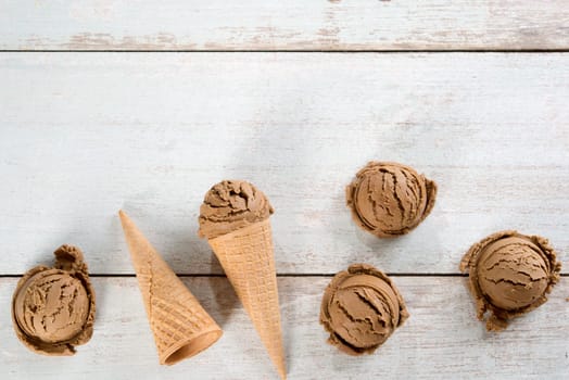 Top view chocolate ice cream in waffle cone on rustic vintage wooden background. Copy space on above.