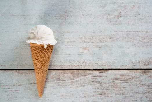 Top view yoghurt ice cream wafer cone on white rustic wooden background. Copy space on side.