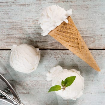 Top view milk ice cream wafer cone on white rustic wooden background.
