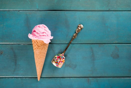 Top view strawberry ice cream waffle cone on blue wooden background.