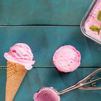 Top view pink ice cream waffle cone on blue wooden background