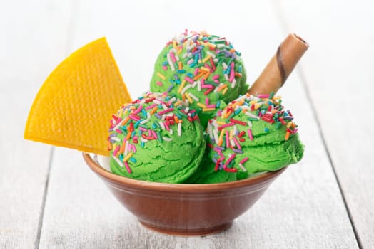 Green ice cream in bowl on wooden background.