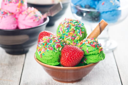 Green ice cream in bowl on wooden background.