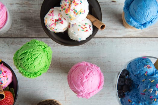 Top view different color ice cream in bowl on white rustic wooden background.