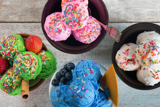 Top view strawberry, matcha, blueberry and vanilla ice cream in bowl on white rustic wooden background.