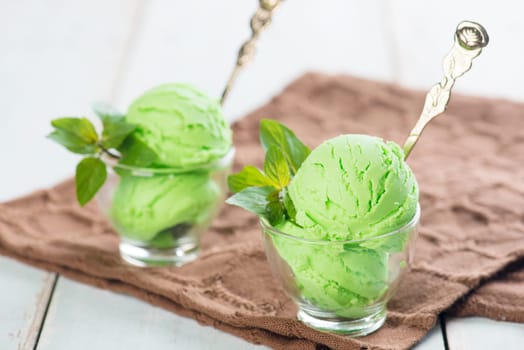 Cups of green ice cream on wooden background.