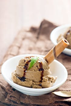 Close up plate of chocolate ice cream with syrup on dining table.