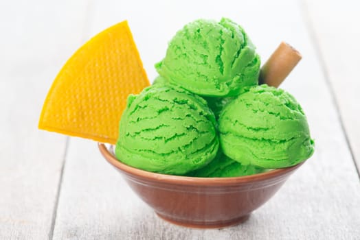 Honeydew ice cream in bowl on wooden background.