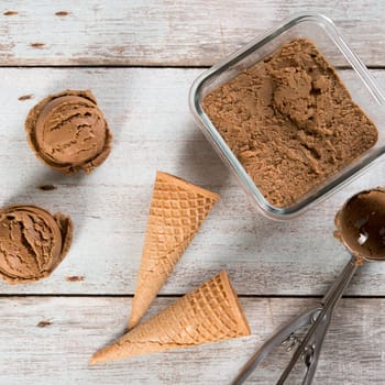 Top view cocoa ice cream with waffle cone on old rustic vintage wooden background.