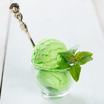 Cup of honeydew ice cream on wooden background.