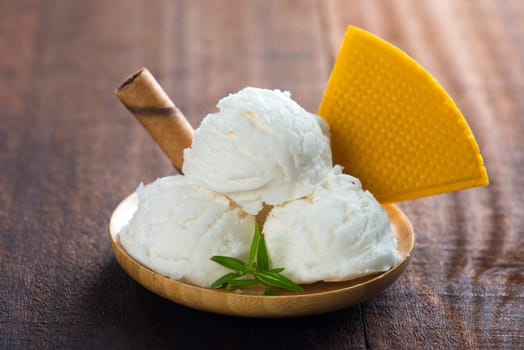 Milk ice cream in plate with waffle on white rustic wooden background.