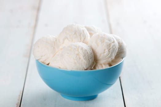 Yogurt ice cream in bowl on white rustic wooden background.