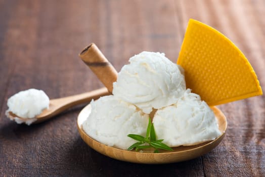 Coconut ice cream in plate with waffle on white rustic wooden background.