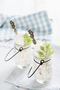 Yoghurt ice cream in cup on white rustic wooden background.