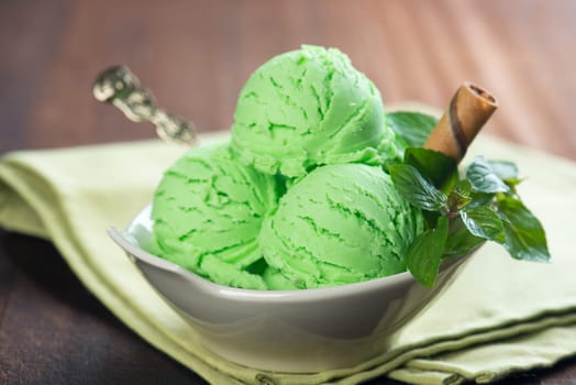 Mint ice cream in bowl on wooden background.