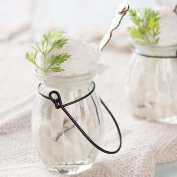 Coconut ice cream in cup on white wooden background.