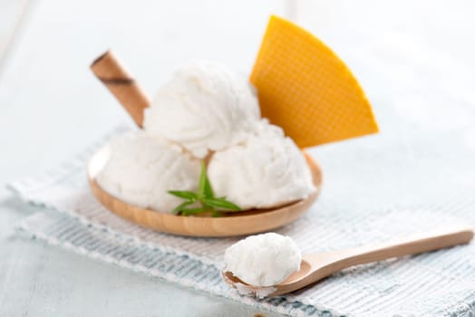 Vanilla ice cream in plate with waffle on white rustic wooden background.