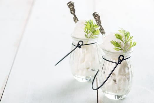 White ice cream in cup on bright rustic wooden background.