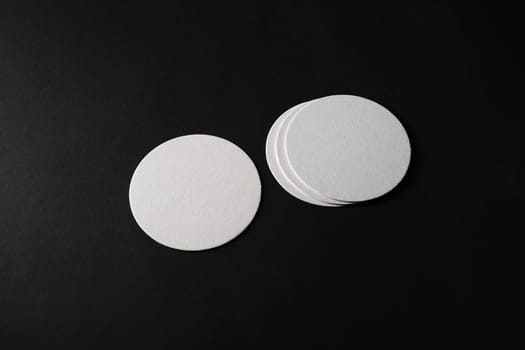 Blank white beer coasters on black paper background. Responsive design mockup.