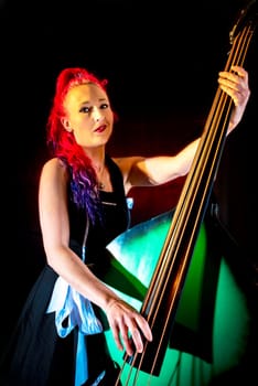 Rock'n'Roll singer with red hair and double bass against a dark background