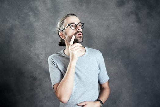 young bearded man with glasses is reflecting