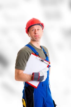 young workman in blue dungarees with clipboard looking sceptical