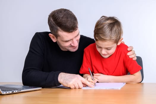 father helping his son with homework at table