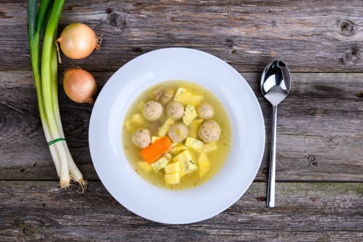 marrow balls soup in white plate with onion on wooden ground