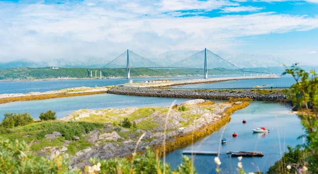 Panorama of bridge and car road in Norway, Europe. Auto travel through scandinavia. Blue cloudy sky, lake and bridge in background.