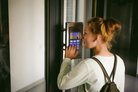 young blond teenager schoolgirl dials the code for a call over the intercom