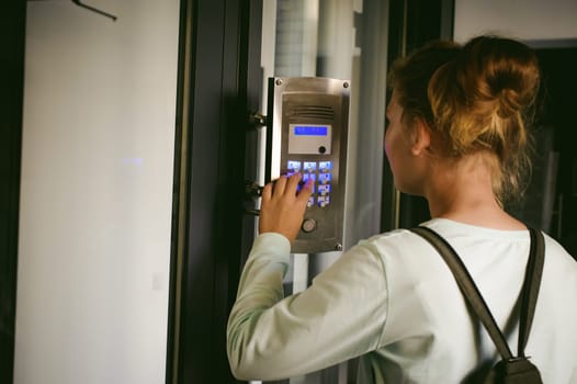 young blond teenager schoolgirl dials the code for a call over the intercom
