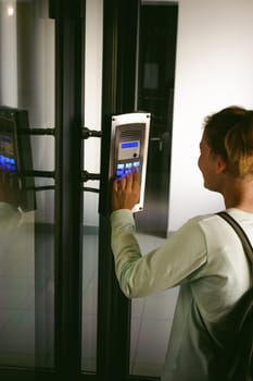 young blond teenager schoolgirl dials the code for a call over the intercom
