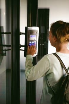 young blond teenager schoolgirl dials the code for a call over the intercom