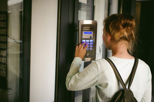 young blond teenager schoolgirl dials the code for a call over the intercom