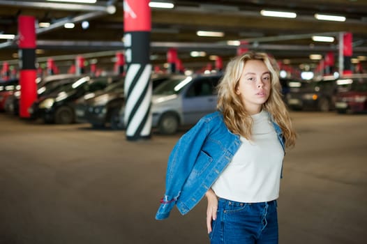 young beautiful woman in jeans clothes in parking of shopping center. portrait of a girl with freckles on her face