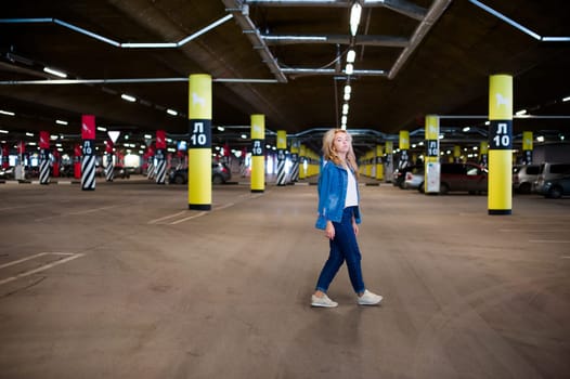 young beautiful woman in jeans clothes in parking of shopping center. portrait of a girl with freckles on her face