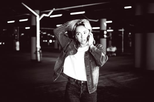 young beautiful woman in jeans clothes in parking of shopping center. portrait of a girl with freckles on her face, stylish girl standing with a cell phone