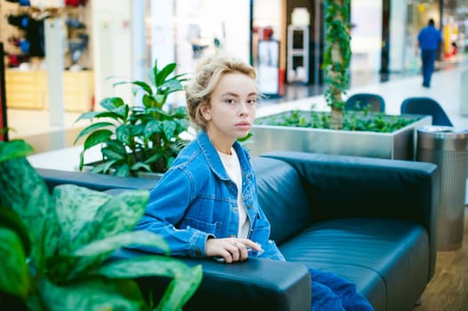 young beautiful woman in jeans clothes in business space of shopping center. portrait of a girl with freckles on her face