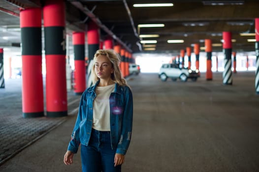 young beautiful woman in jeans clothes in parking of shopping center. portrait of a girl with freckles on her face