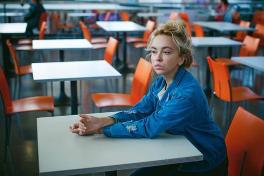 young beautiful woman in jeans clothes in business space of shopping center. portrait of a girl with freckles on her face, stylish girl in an empty cafe