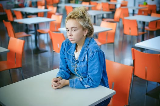 young beautiful woman in jeans clothes in business space of shopping center. portrait of a girl with freckles on her face, stylish girl in an empty cafe