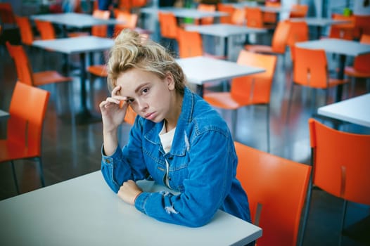 young beautiful woman in jeans clothes in business space of shopping center. portrait of a girl with freckles on her face, stylish girl in an empty cafe