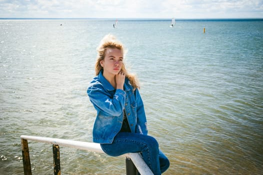 young beautiful woman in jeans clothes outdoors. portrait of a girl with freckles on her face, stylish girl on sea beach, on a sunny summer autumn day.