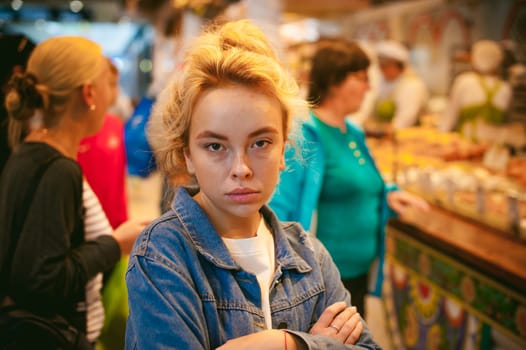young beautiful woman in jeans clothes in business space of shopping center. portrait of a girl with freckles on her face, stylish girl standing near show-windows of fair in shopping center