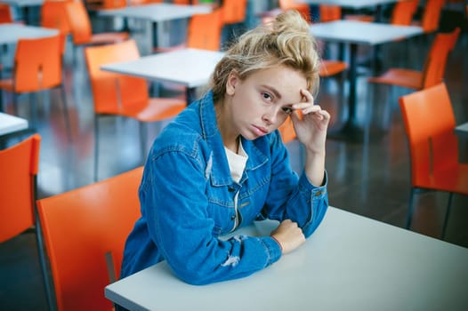 young beautiful woman in jeans clothes in business space of shopping center. portrait of a girl with freckles on her face, stylish girl in an empty cafe