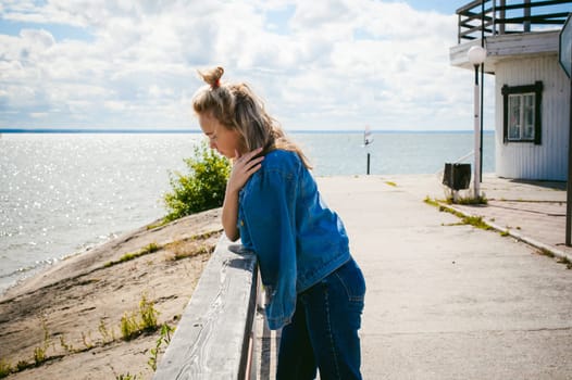 young beautiful woman in jeans clothes outdoors. portrait of a girl with freckles on her face, stylish girl on sea beach, on a sunny summer autumn day.